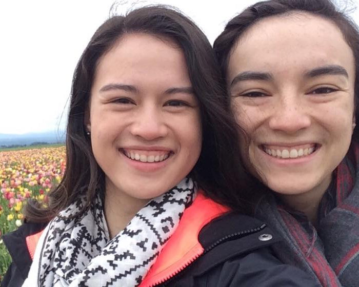 Two people smiling in front of a field of colorful flowers.